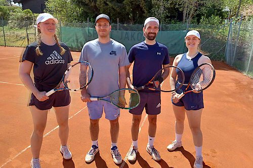 Zwei Männer und zwei Frauen stehen lächelnd mit Tennisschlägern auf einem Platz Trainingswoche für vier Personen im Bayerischen Wald